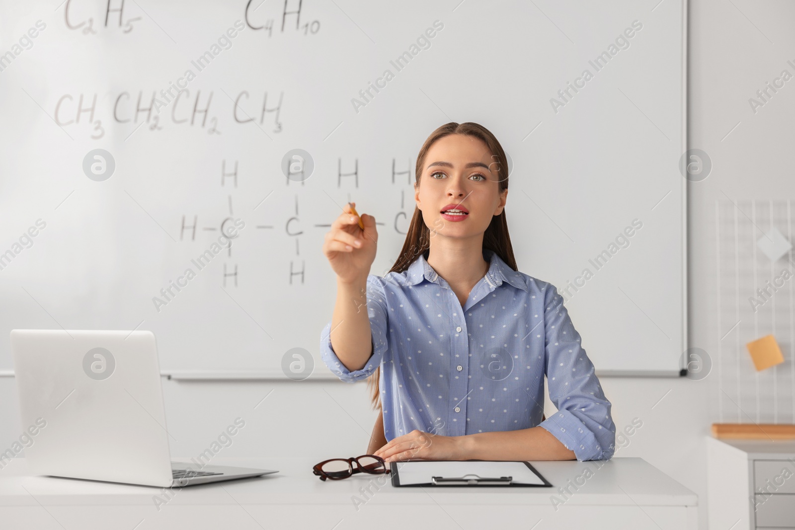 Photo of Young chemistry teacher giving lesson at table in classroom