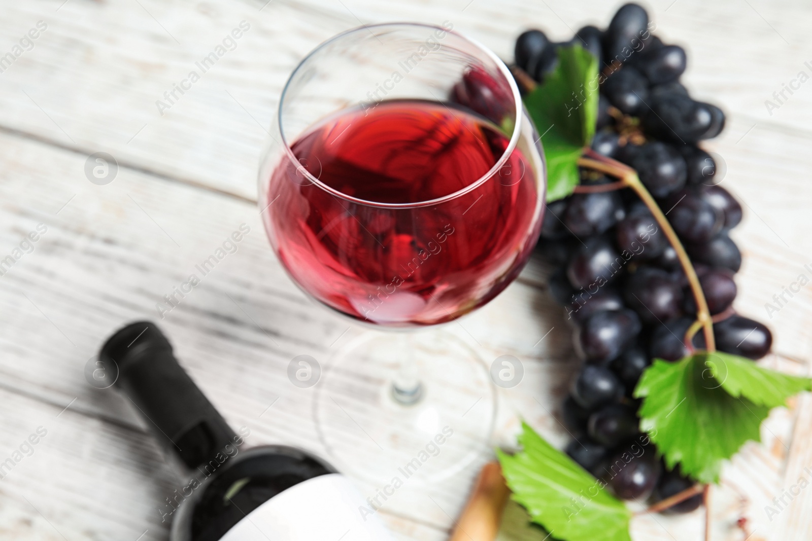 Photo of Glass and bottle of red wine with fresh ripe juicy grapes on table