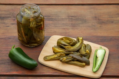 Fresh and pickled green jalapeno peppers on wooden table