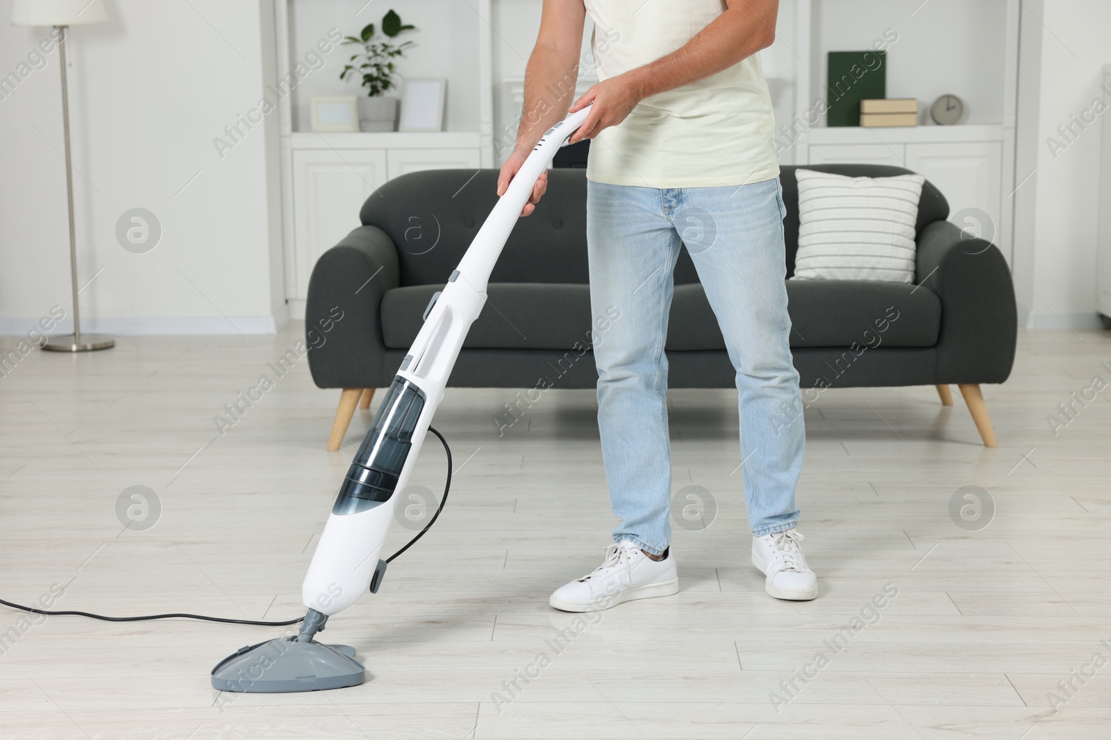 Photo of Man cleaning floor with steam mop at home, closeup