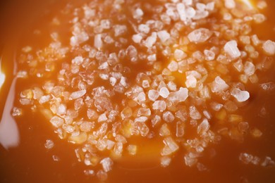 Photo of Delicious caramel sauce with sea salt as background, closeup