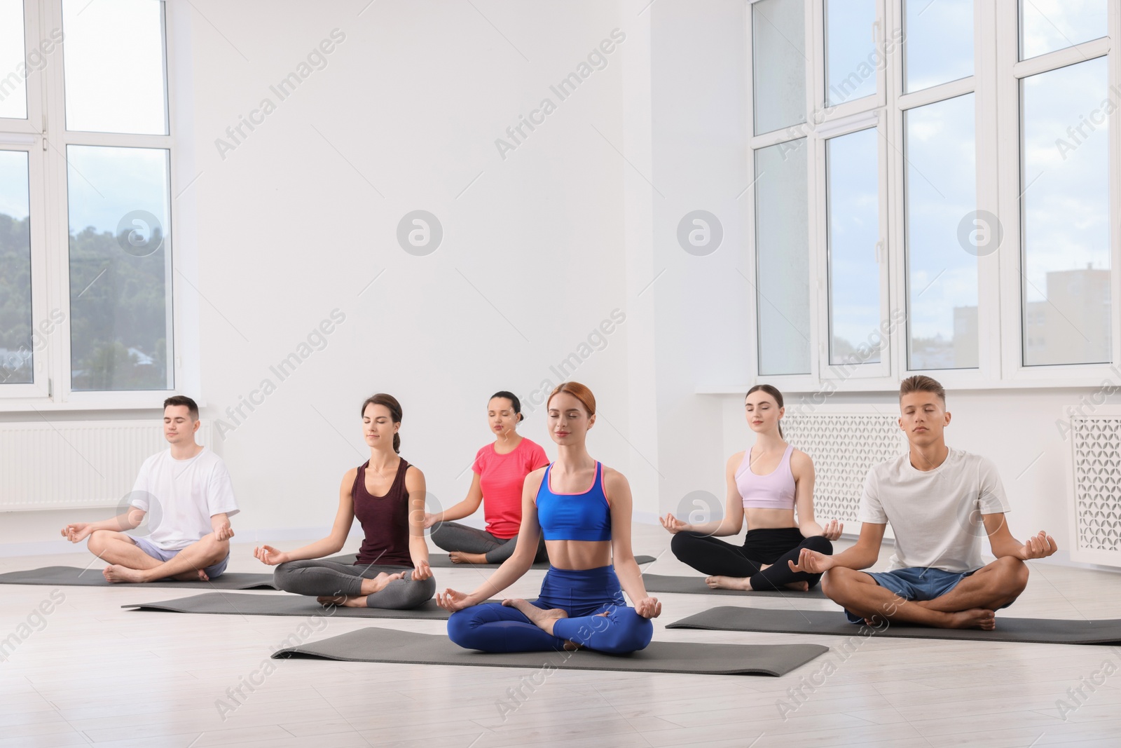 Photo of Group of people practicing yoga on mats indoors, space for text