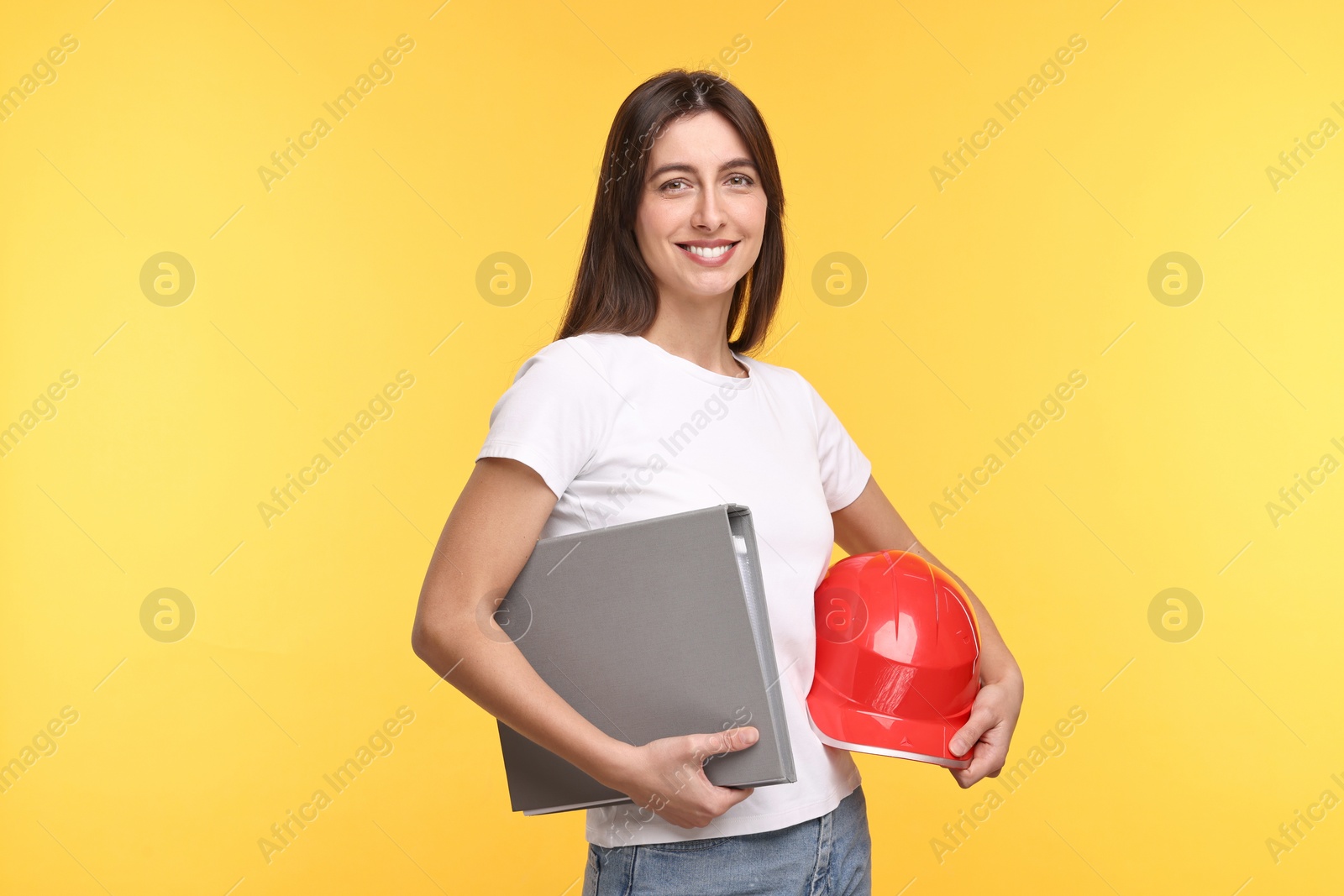 Photo of Architect with hard hat and folder on yellow background