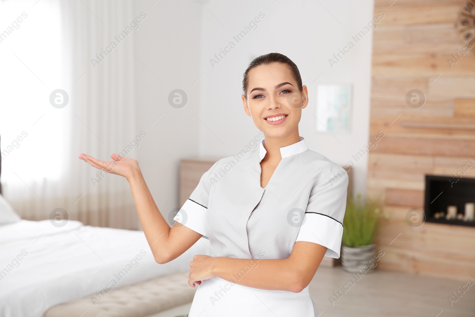 Photo of Portrait of pretty young chambermaid in hotel room