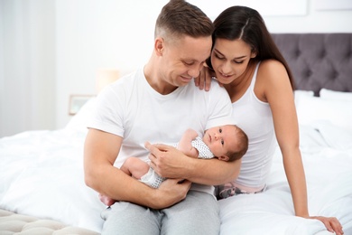 Happy couple with their newborn baby on bed