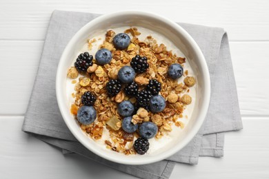 Photo of Bowl of healthy muesli served with berries on white wooden table, top view