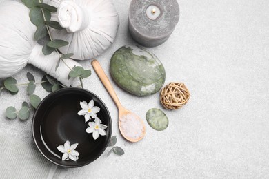 Flat lay composition with herbal massage bags, spa products and flowers on light grey table. Space for text