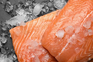 Fresh raw salmon with ice on black table, flat lay