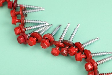 Red self-tapping screws on turquoise background, above view