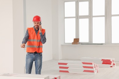 Male industrial engineer in uniform talking on phone indoors