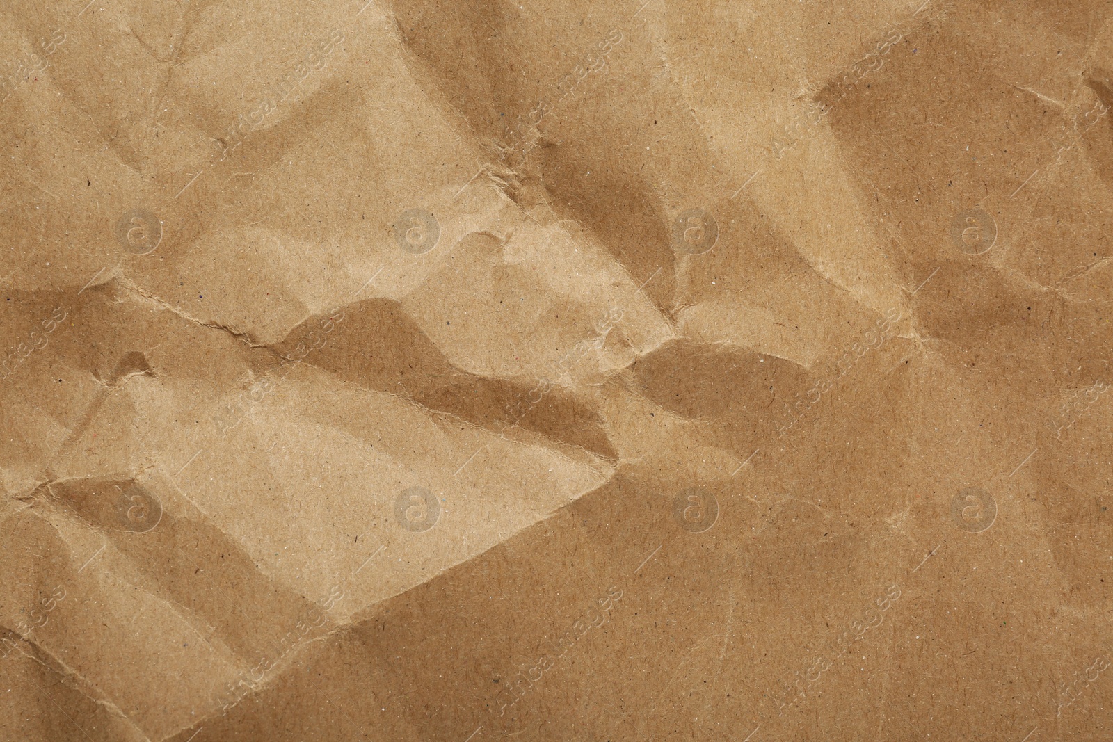 Photo of Crumpled kraft notebook sheet as background, top view