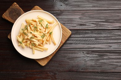 Photo of Delicious french fries with cheese sauce and dill on wooden table, top view. Space for text