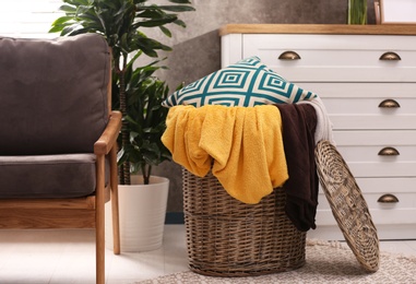 Photo of Basket with blankets and pillow near in room