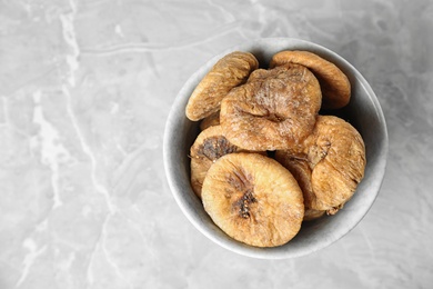 Photo of Bowl of tasty dried figs on light grey marble table, top view. Space for text