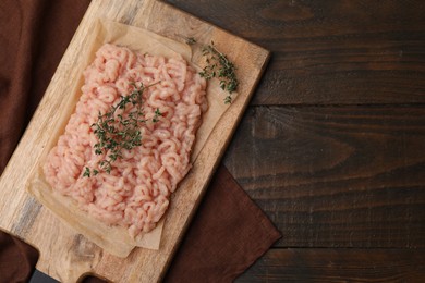 Fresh raw minced meat and thyme on wooden table, top view. Space for text