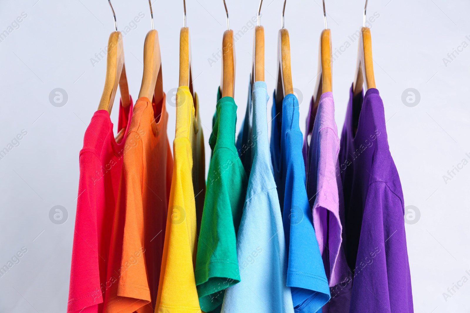 Photo of Colorful clothes on hangers against white background