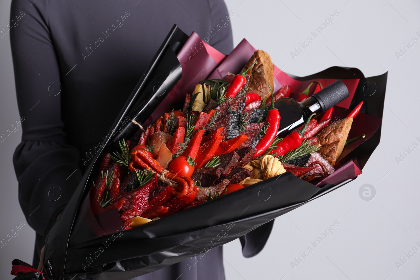 Photo of Woman with beautiful food bouquet on light grey background, closeup