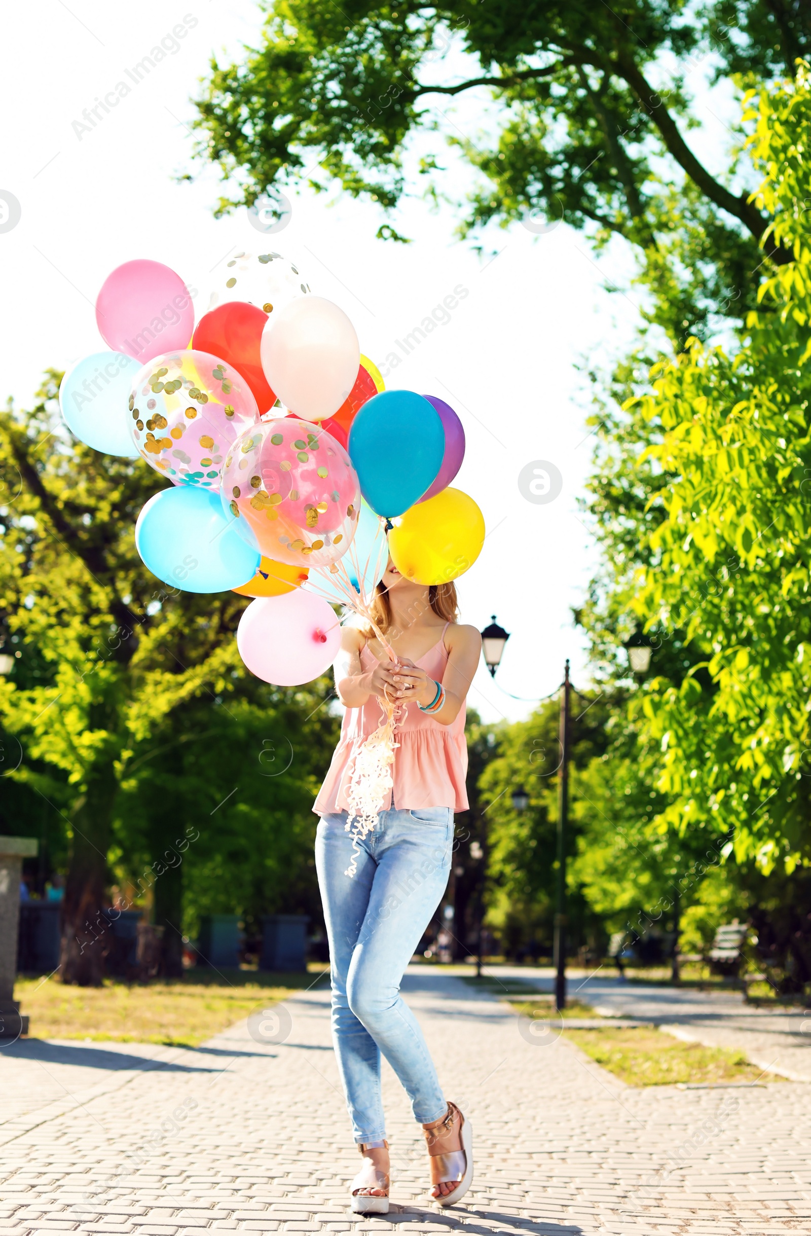 Photo of Young woman with colorful balloons outdoors on sunny day