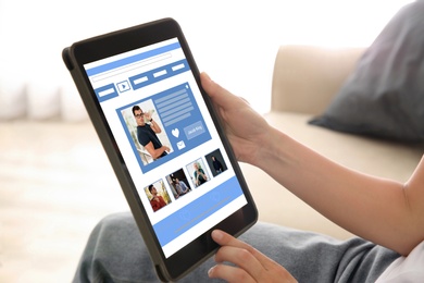 Image of Young woman visiting online dating site via tablet indoors, closeup