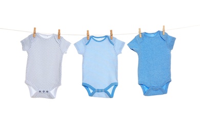 Colorful baby onesies hanging on clothes line against white background. Laundry day