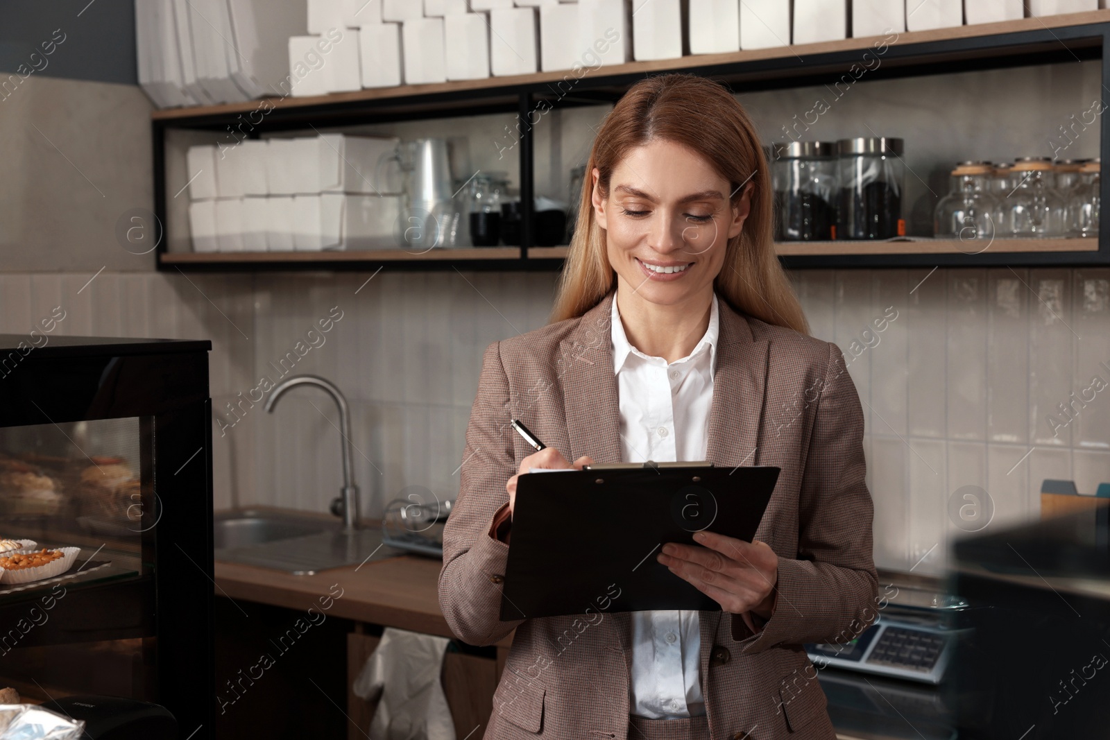 Photo of Happy business owner with clipboard and pen in bakery shop