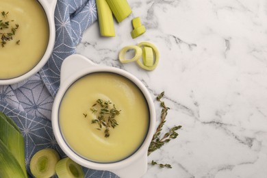 Tasty leek soup in bowls on white marble table, flat lay. Space for text