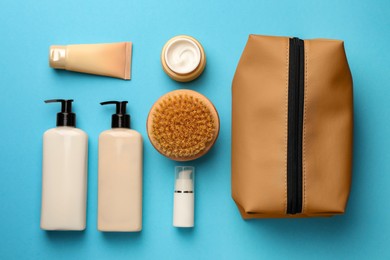 Photo of Preparation for spa. Compact toiletry bag and different cosmetic products on light blue background, flat lay