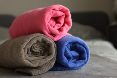 Rolled color sweaters on gray table, closeup