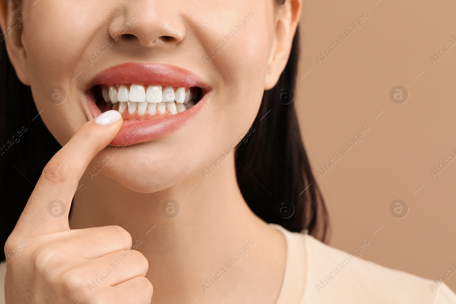 Photo of Woman showing her clean teeth on beige background, closeup