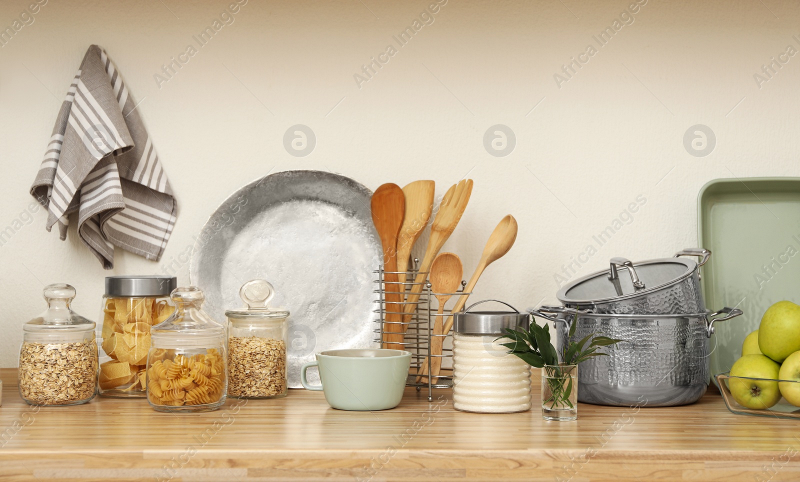 Photo of Wooden countertop with dishware and products near white wall. Kitchen interior idea