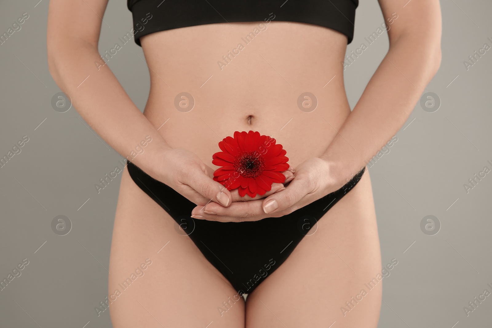 Photo of Gynecology. Woman in underwear with gerbera flower on grey background, closeup