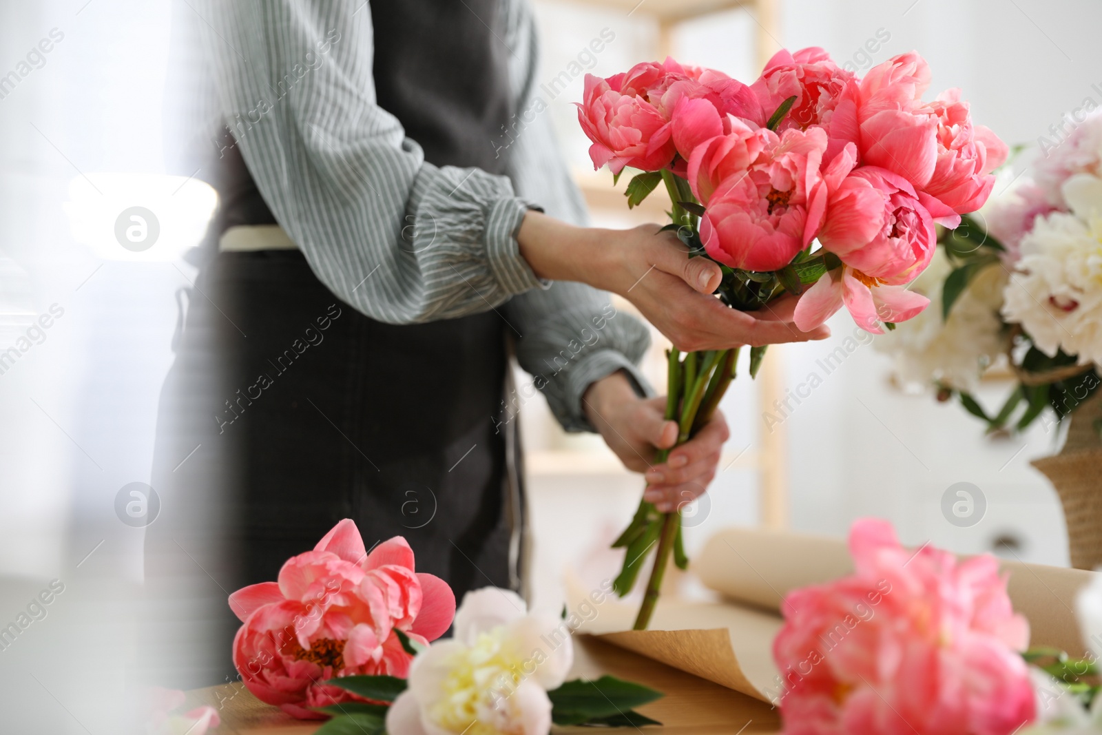 Photo of Florist with beautiful peony bouquet indoors, closeup