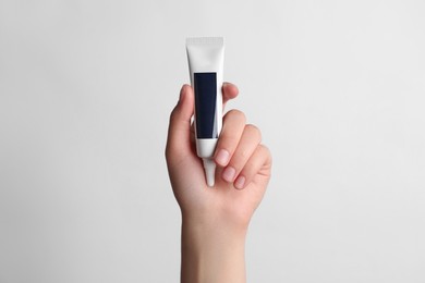 Photo of Woman holding tube of face cream on white background, closeup