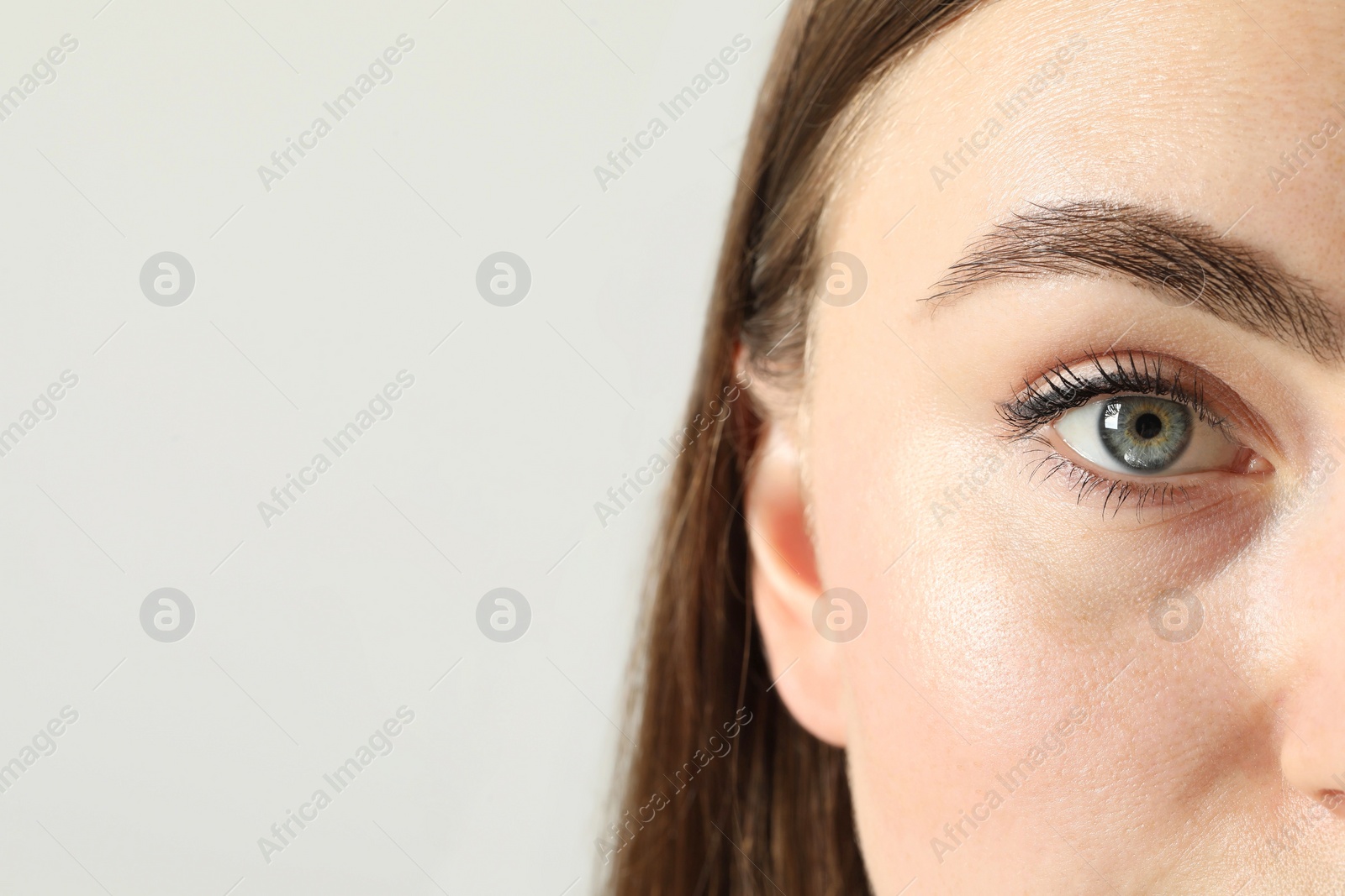 Photo of Closeup photo of woman with beautiful eyes on light background. Space for text