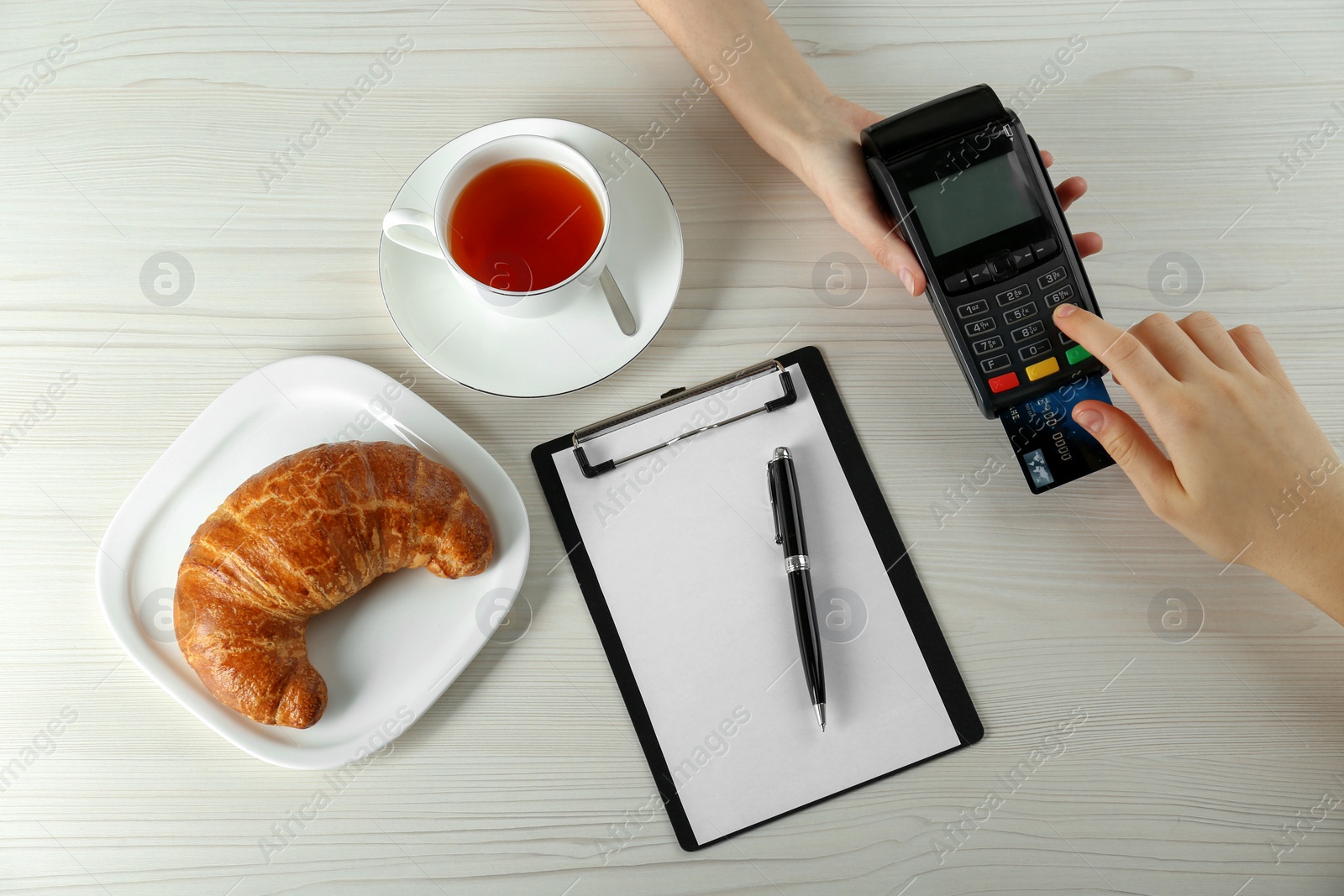 Photo of Woman with credit card using modern payment terminal at white table, top view