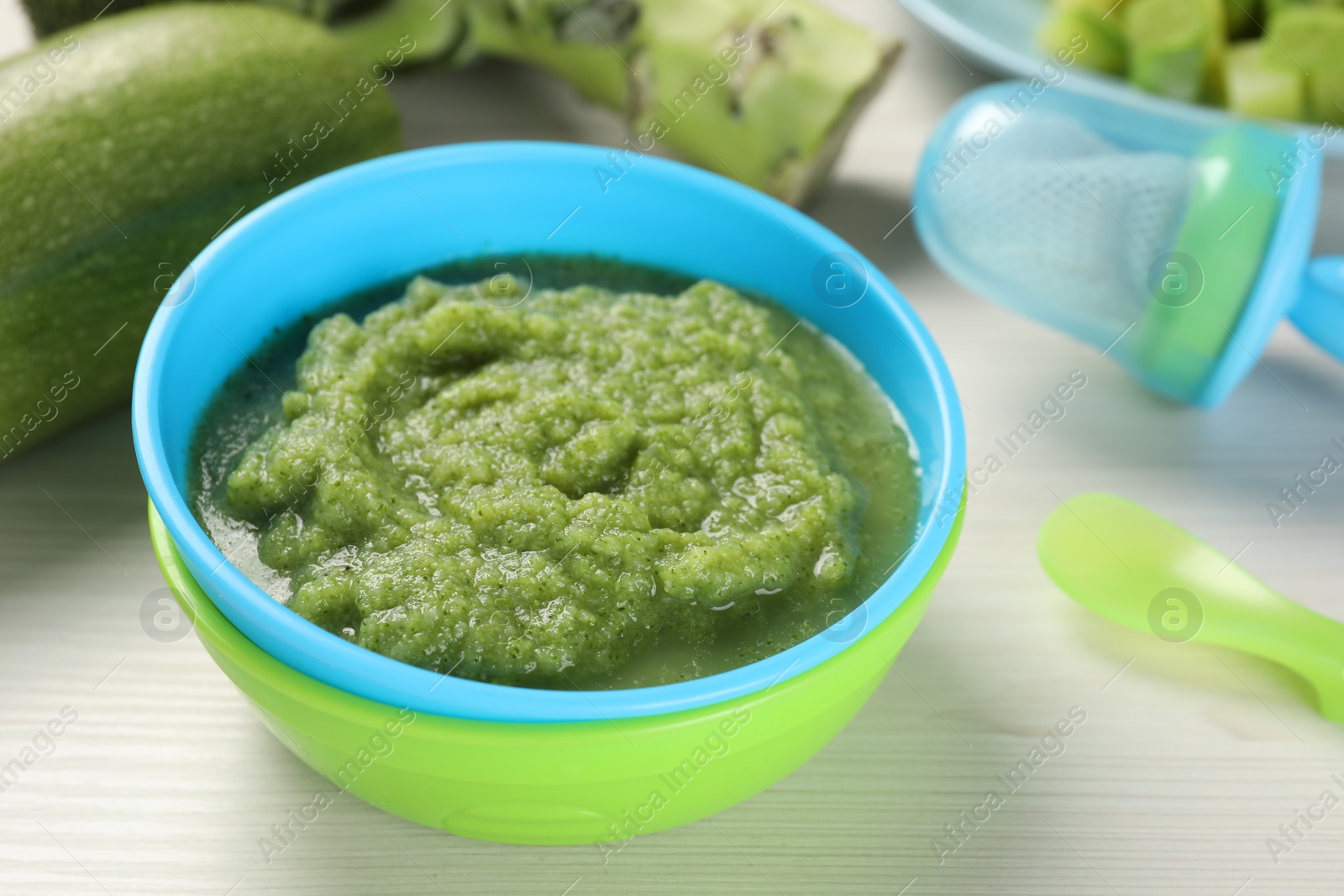 Photo of Healthy baby food. Bowl with tasty broccoli puree on white wooden table, closeup