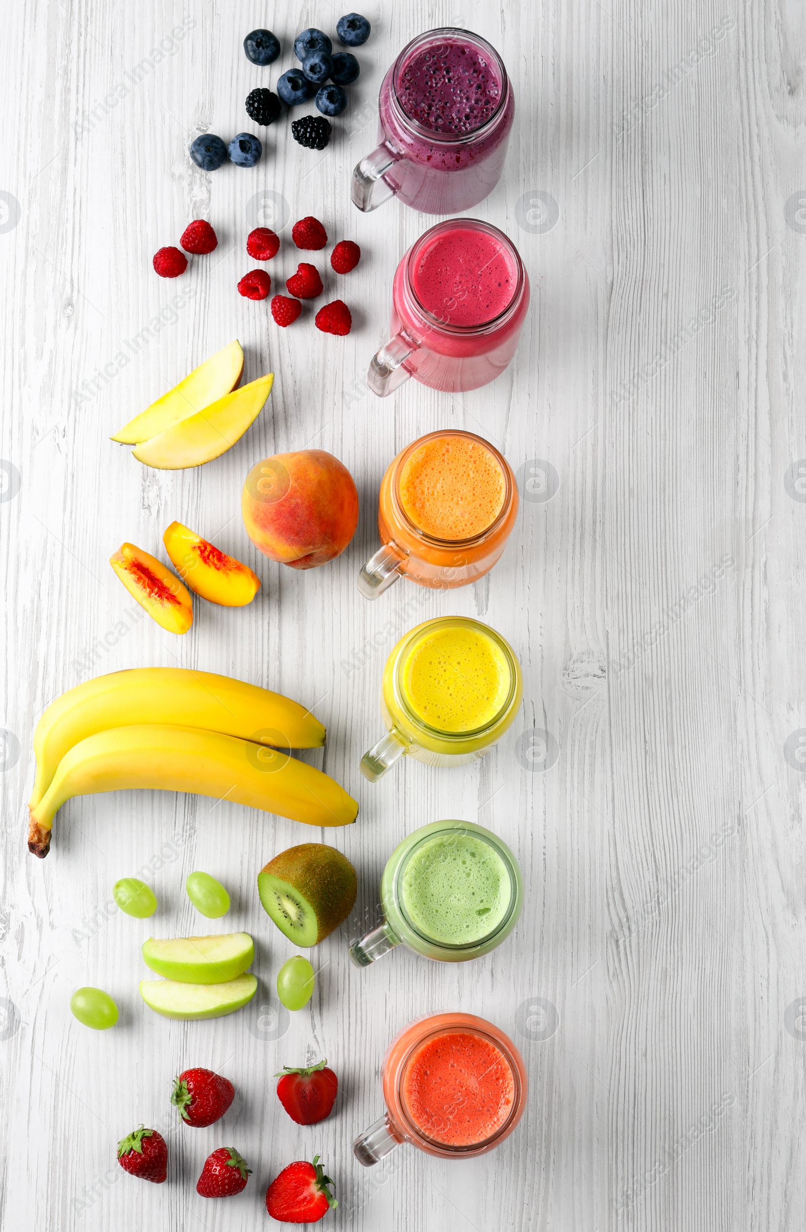 Photo of Many different tasty smoothies and ingredients on white wooden table, flat lay. Space for text