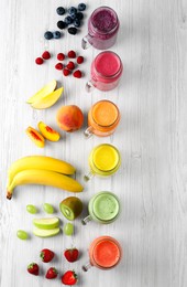 Photo of Many different tasty smoothies and ingredients on white wooden table, flat lay. Space for text