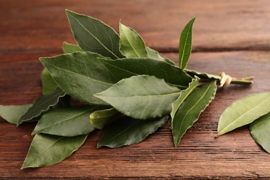 Aromatic fresh bay leaves on wooden table, closeup