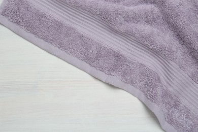 Photo of Violet terry towel on light wooden table, top view. Space for text