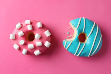 Photo of Sweet tasty glazed donuts on pink background, flat lay
