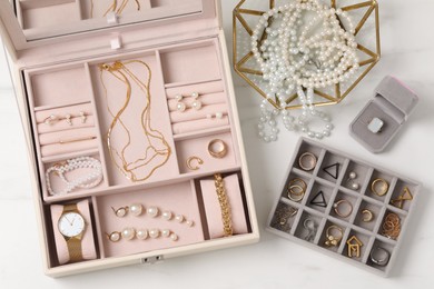 Photo of Jewelry boxes with many different accessories on white marble table, flat lay