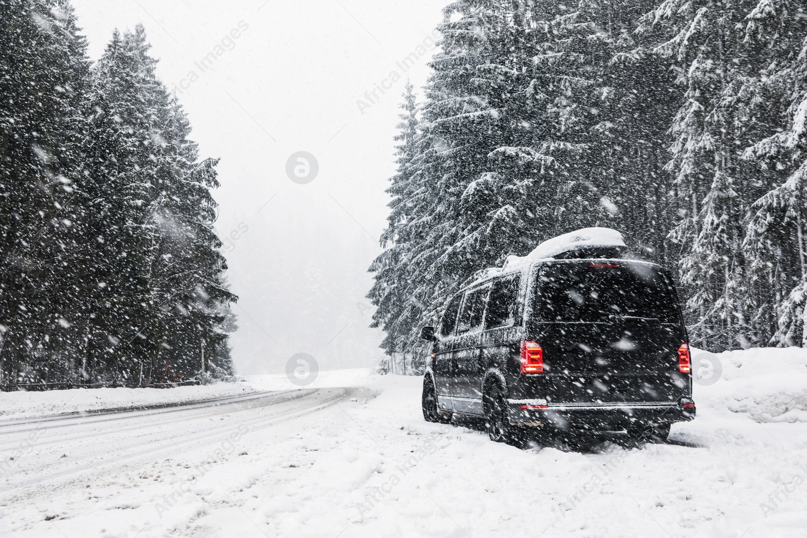 Photo of Modern car on snowy road near forest. Winter vacation