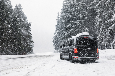 Modern car on snowy road near forest. Winter vacation