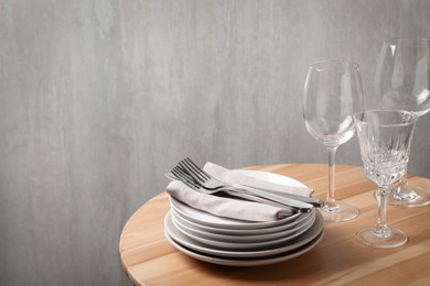 Set of clean dishware, glasses and cutlery on wooden table, space for text