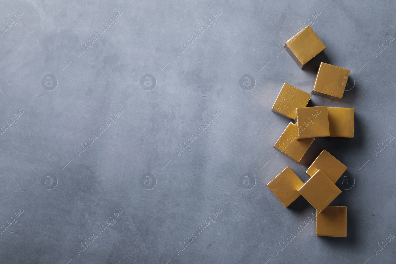 Photo of Golden cubes on grey table, flat lay. Space for text