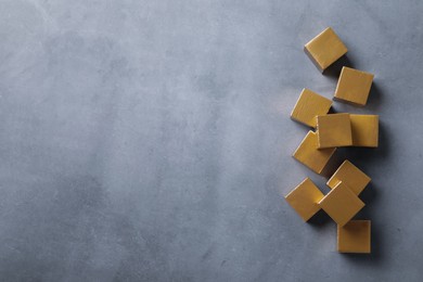 Photo of Golden cubes on grey table, flat lay. Space for text