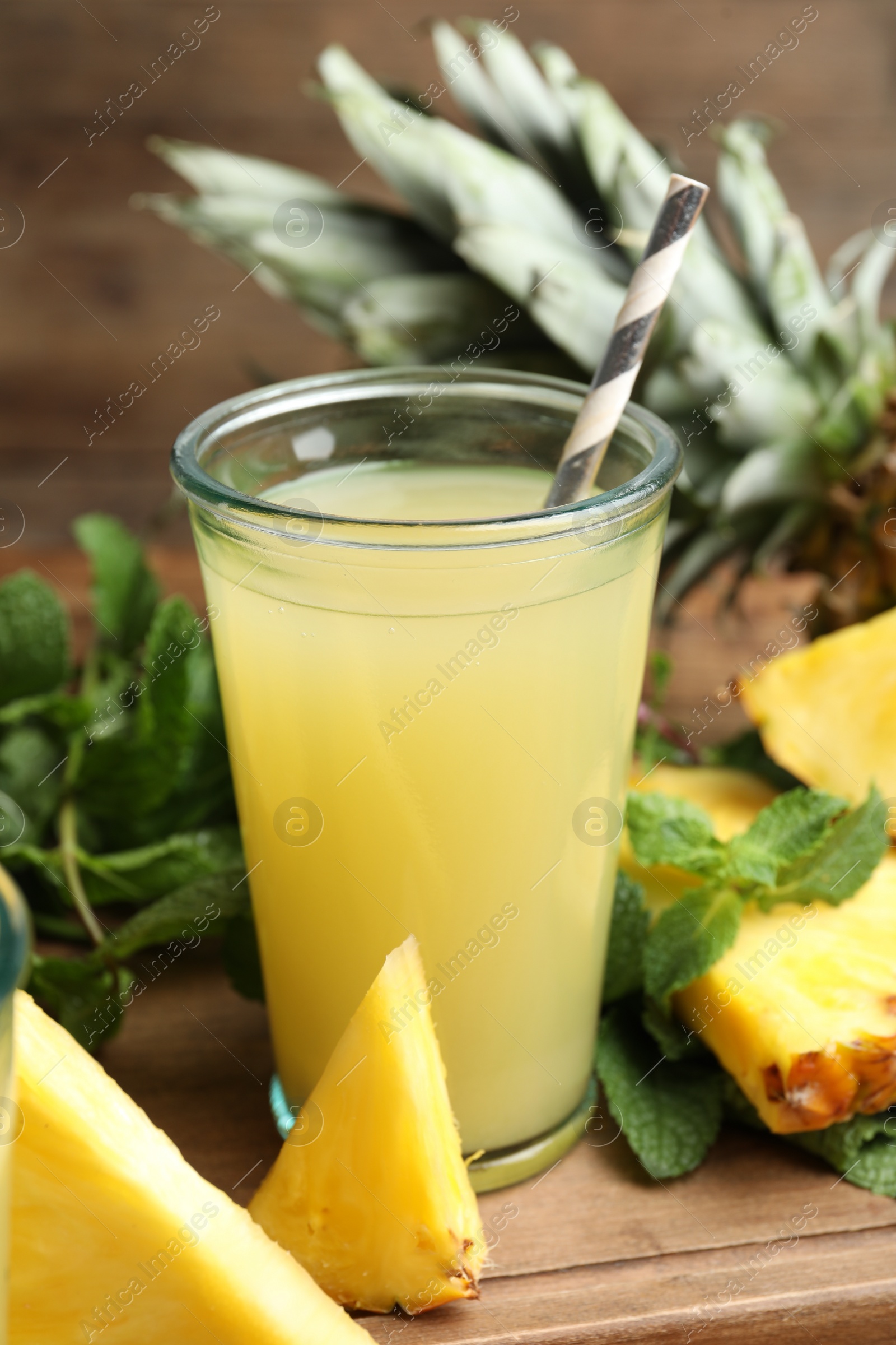 Photo of Delicious pineapple juice and fresh fruit on wooden table