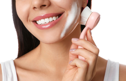 Photo of Young woman using facial cleansing brush on white background, closeup. Washing accessory