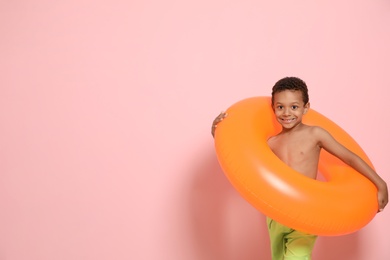 Cute African American boy with bright inflatable ring on color background